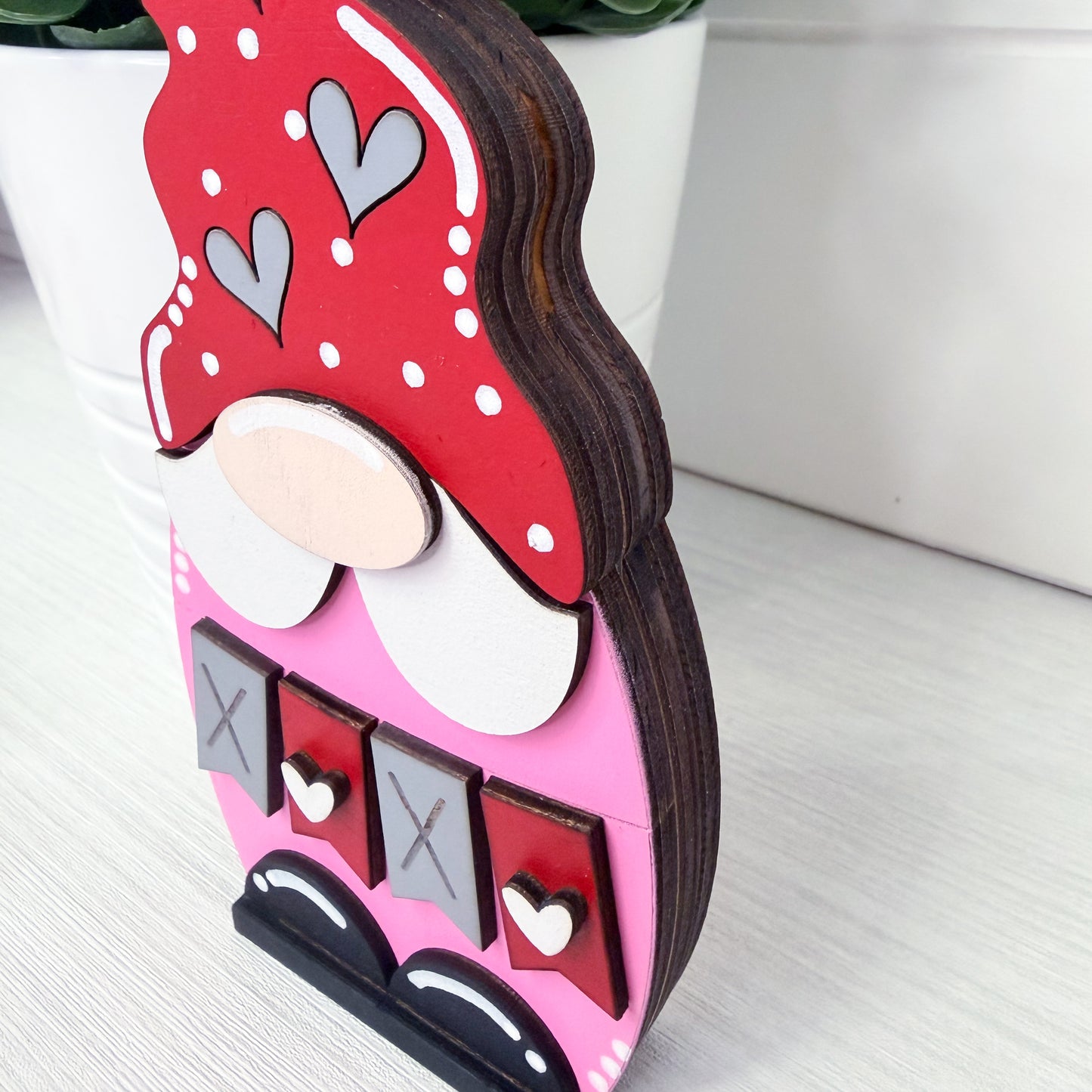 Decorative gnome with a red hat and heart patterns on a white surface