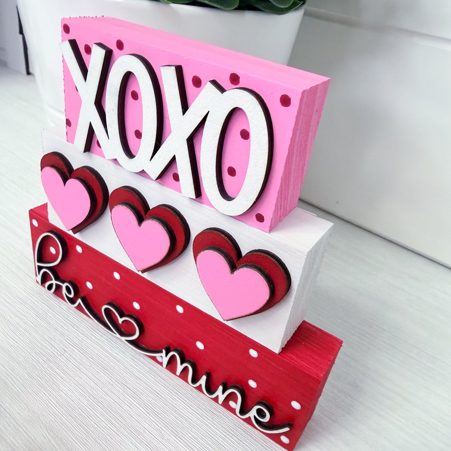 Decorative sign with 'XOHO' and heart designs on a white surface