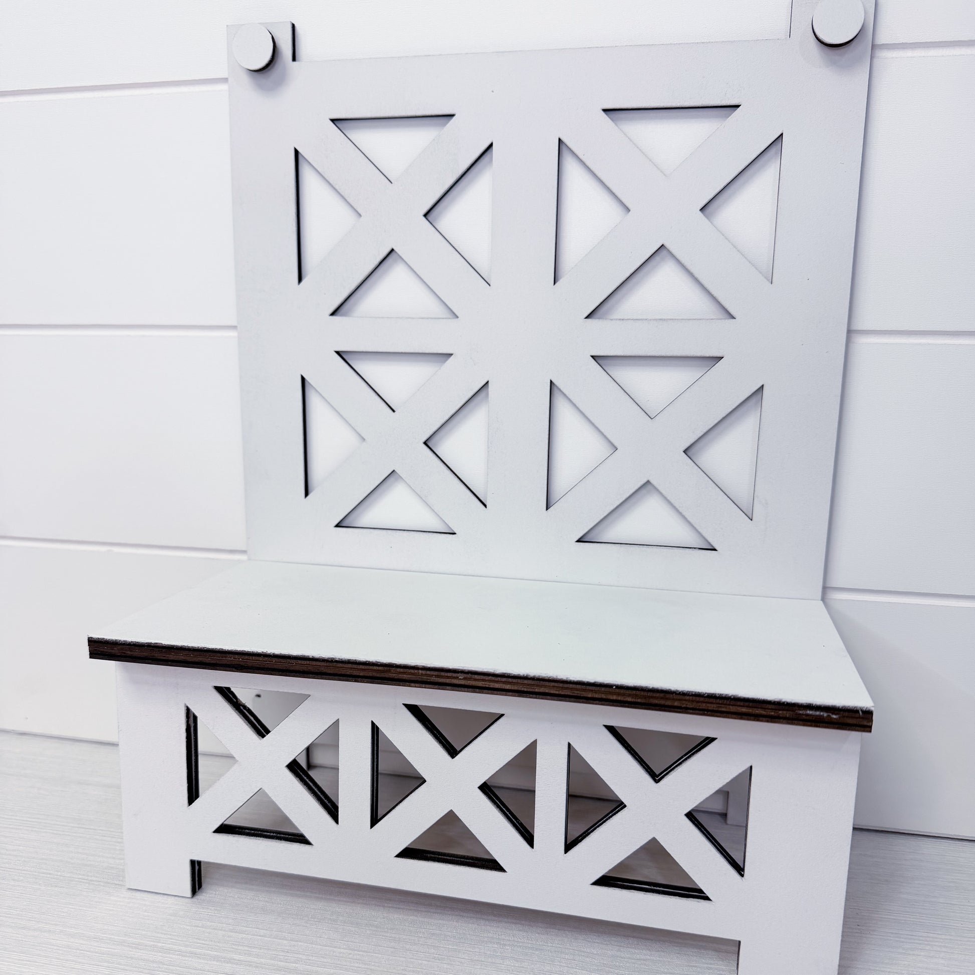 White bench with decorative backrest against a white wooden panel background