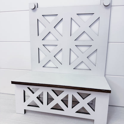 White bench with decorative backrest against a white wooden panel background