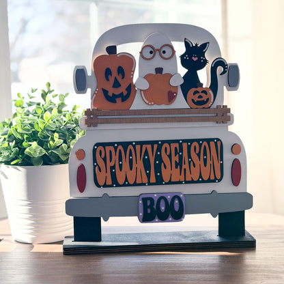 Halloween-themed decorative sign with pumpkins, ghost, and cat on a truck bed, featuring 'Spooky Season' and 'Boo' text.