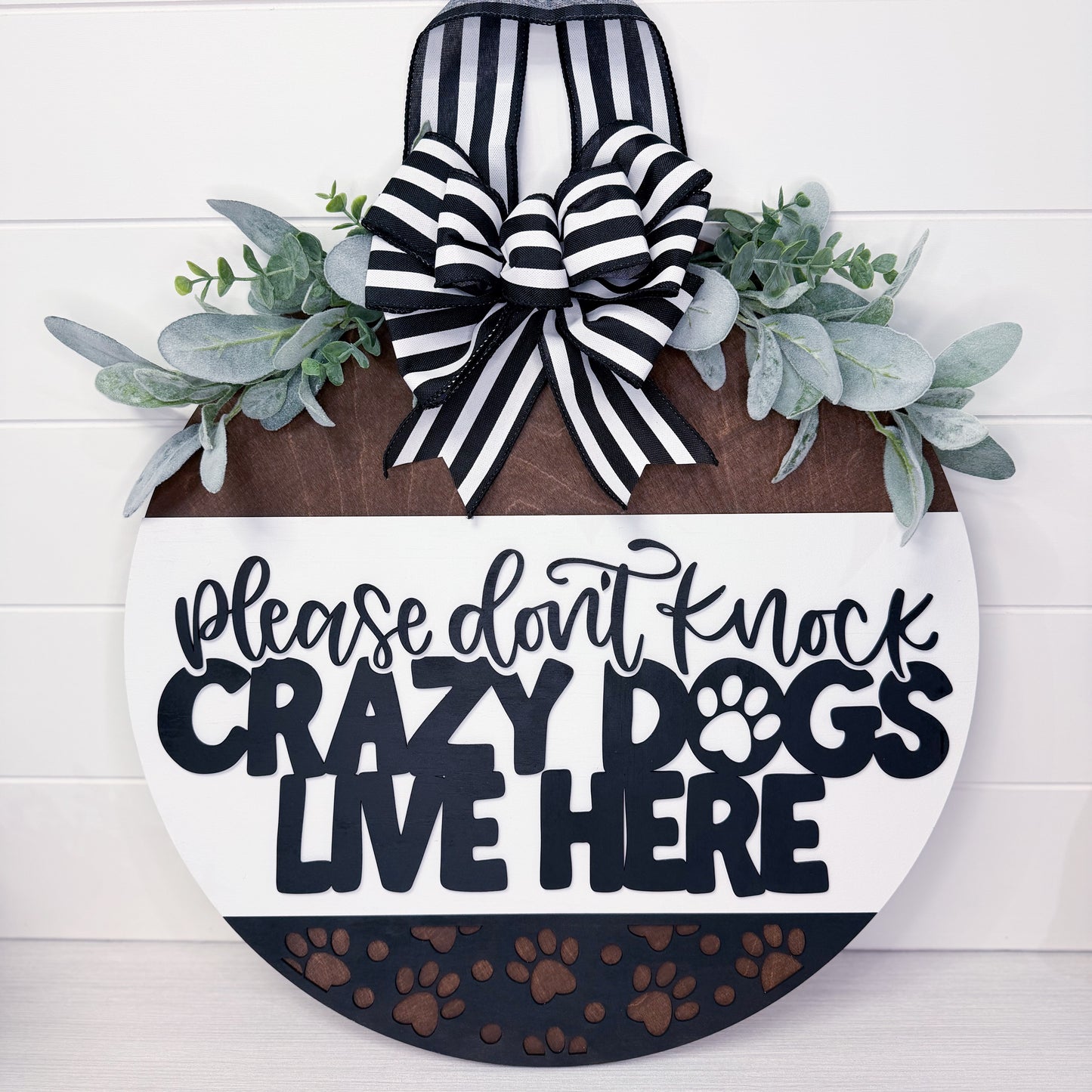 Decorative sign with text 'Please don't knock crazy dogs live here' and a bow on a white background