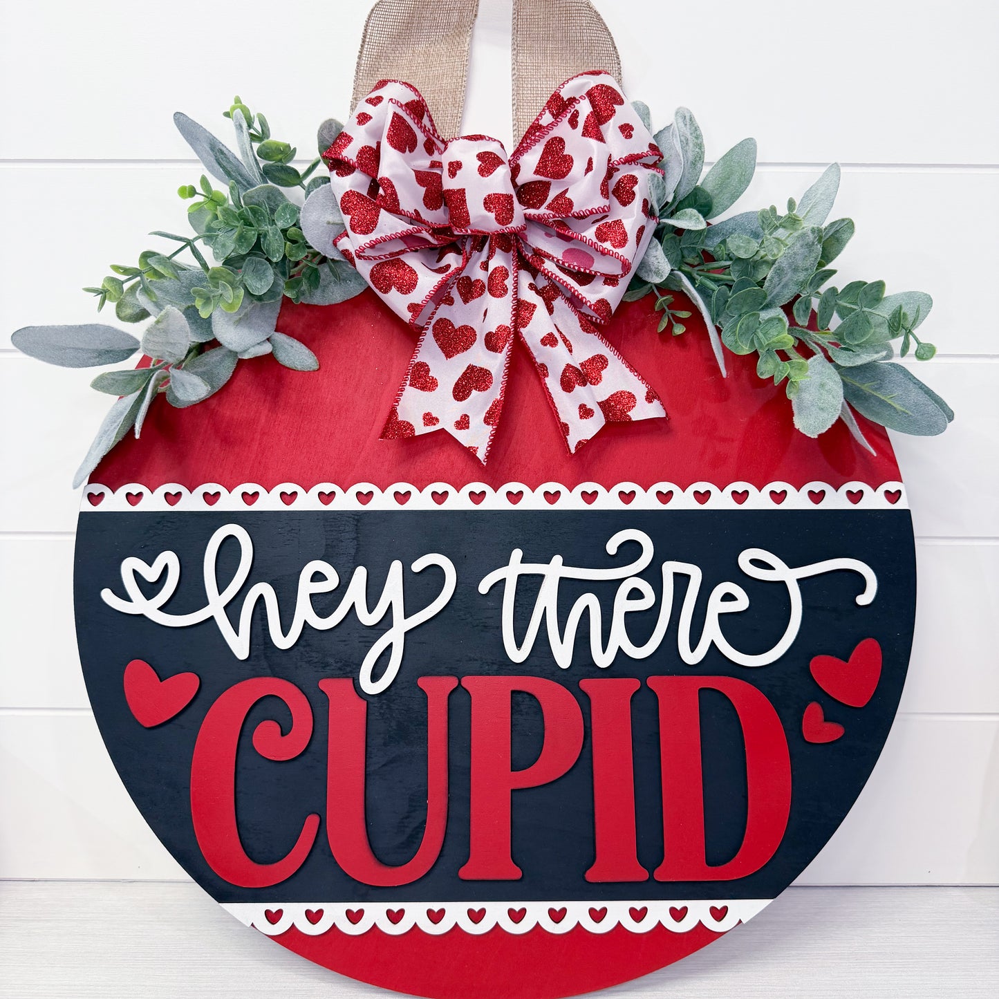 Decorative sign with a heart shape, bow, and 'hey there Cupid' text on a white background