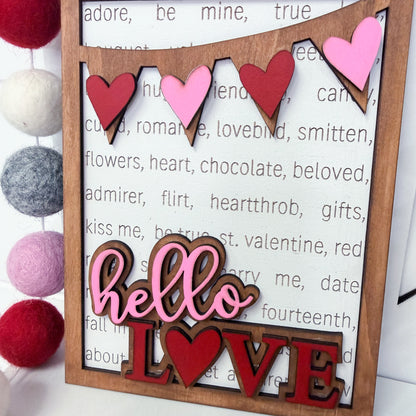 Wooden sign with 'hello love' and heart shapes on a textured background
