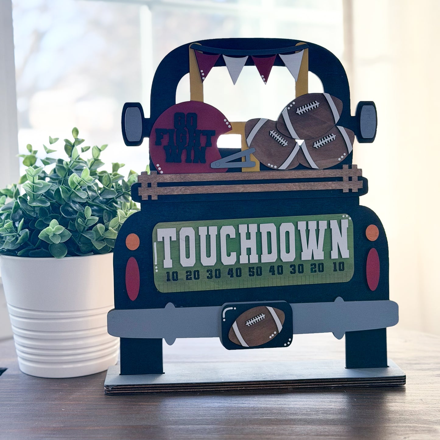 Decorative paper model of a pickup truck with football-themed items on a wooden surface.