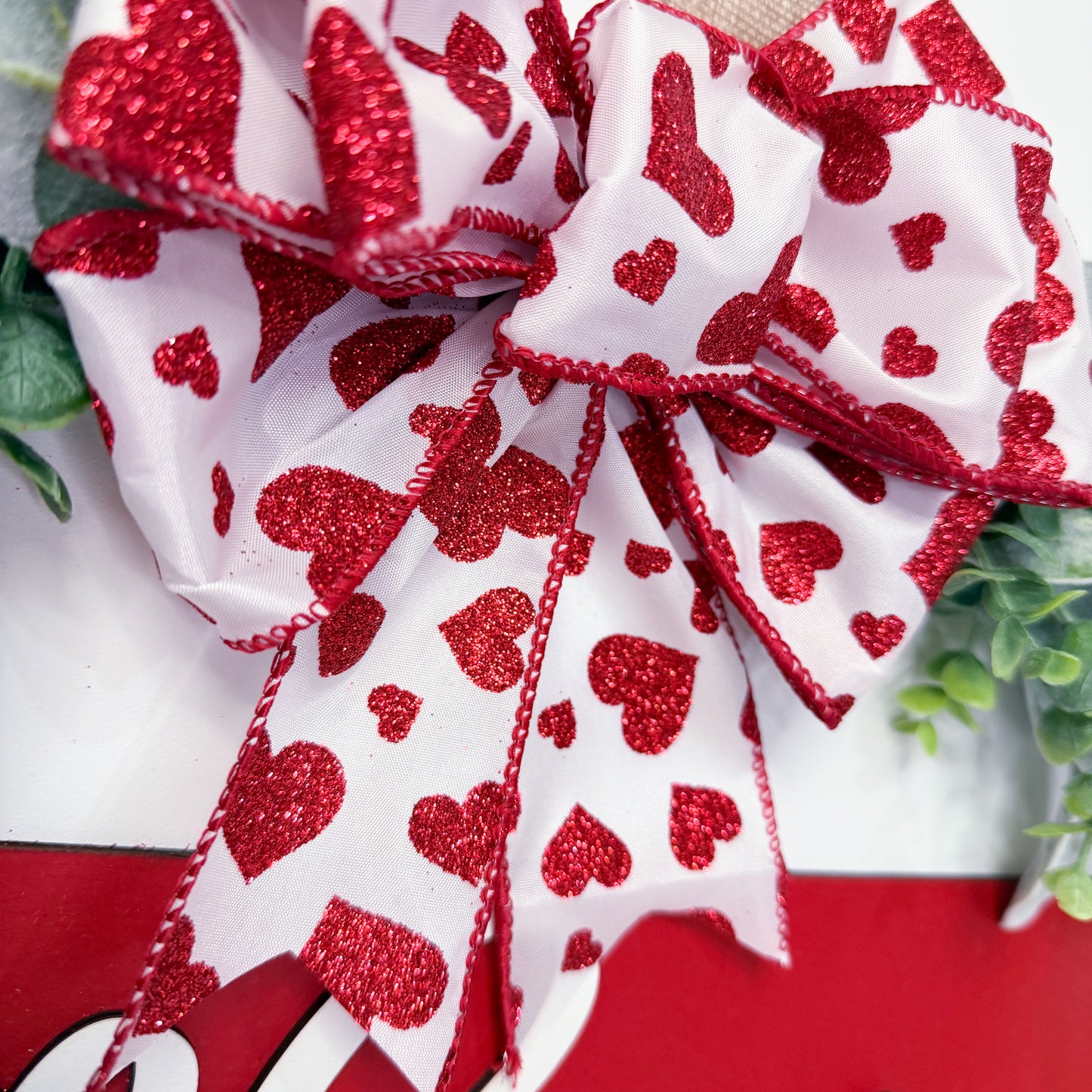 Red and white decorative bow with heart pattern on a red background
