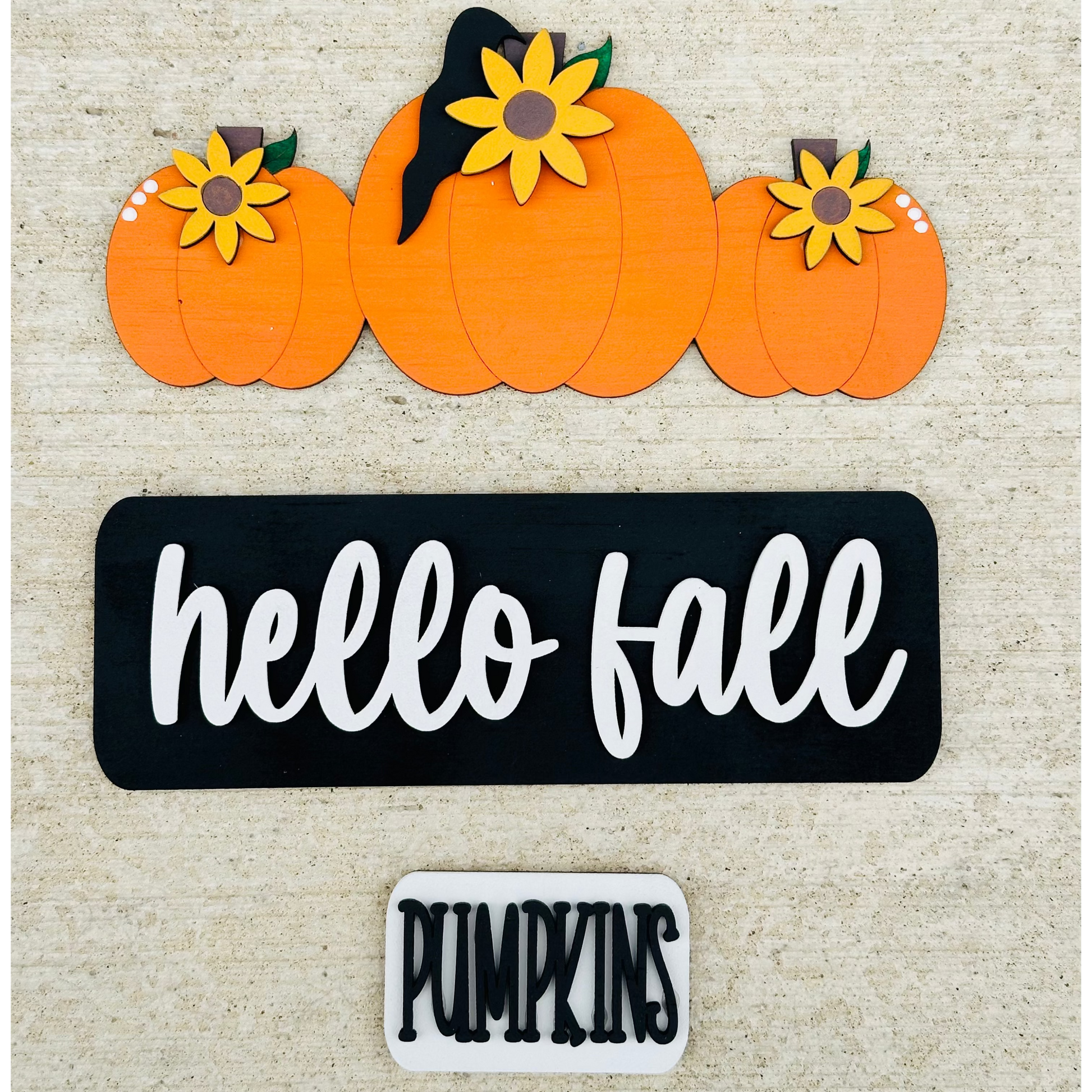 A decorative wood truck with 'hello fall' and 'pumpkin' text, carrying pumpkins on its bed, placed on a table.