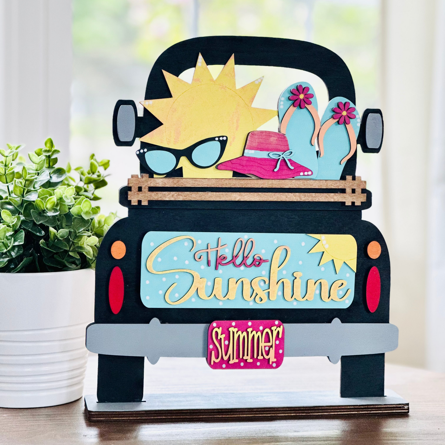 A decorative wood insert featuring a colorful illustration of a sun wearing sunglasses and a hat, with text that reads 'Hello Sunshine' and 'Summer'. The piece is designed to be interchangeable and is part of a seasonal home decor set.