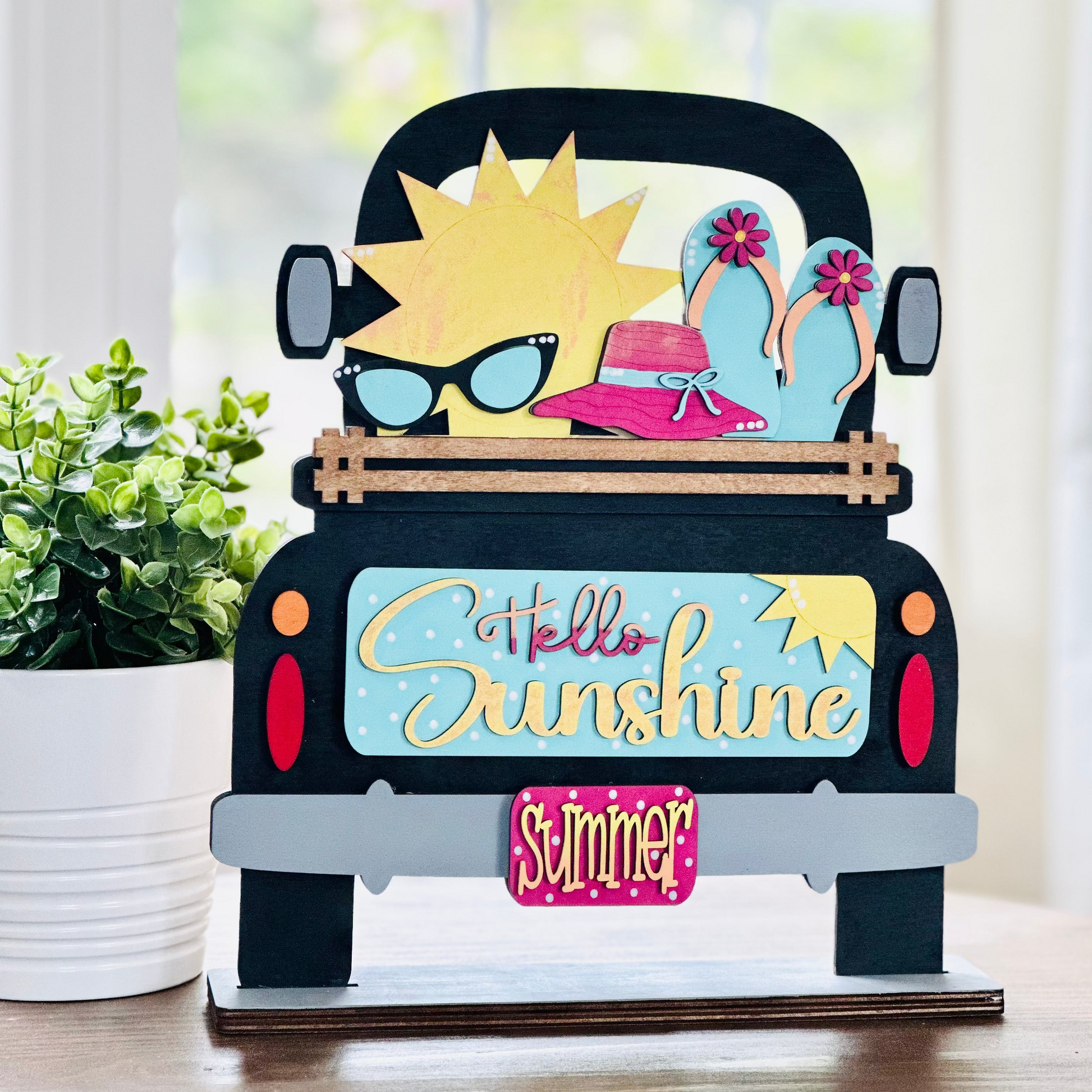 A decorative wood insert featuring a colorful illustration of a sun wearing sunglasses and a hat, with text that reads 'Hello Sunshine' and 'Summer'. The piece is designed to be interchangeable and is part of a seasonal home decor set.