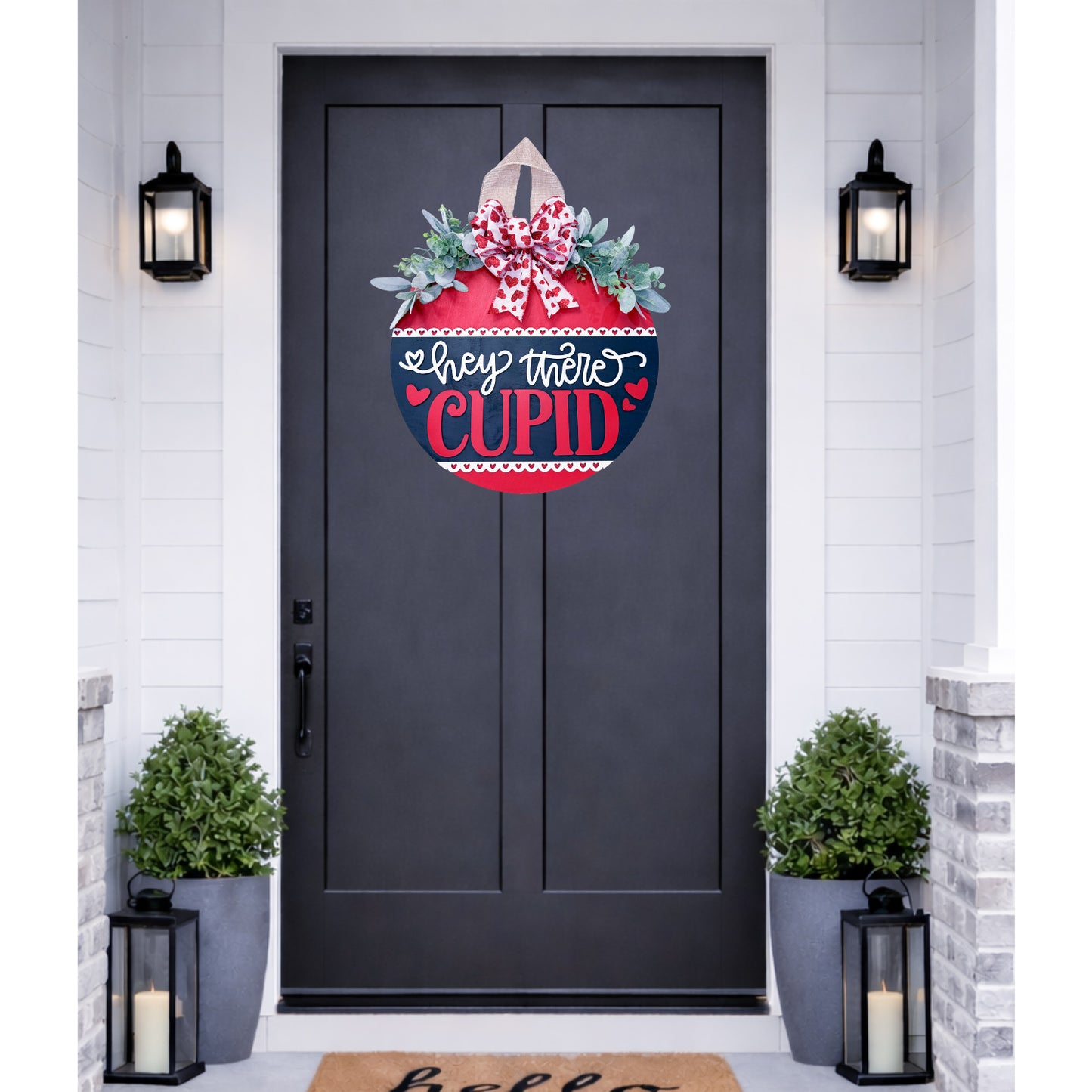 Decorative door hanger with 'Hey There Cupid' text on a black door.
