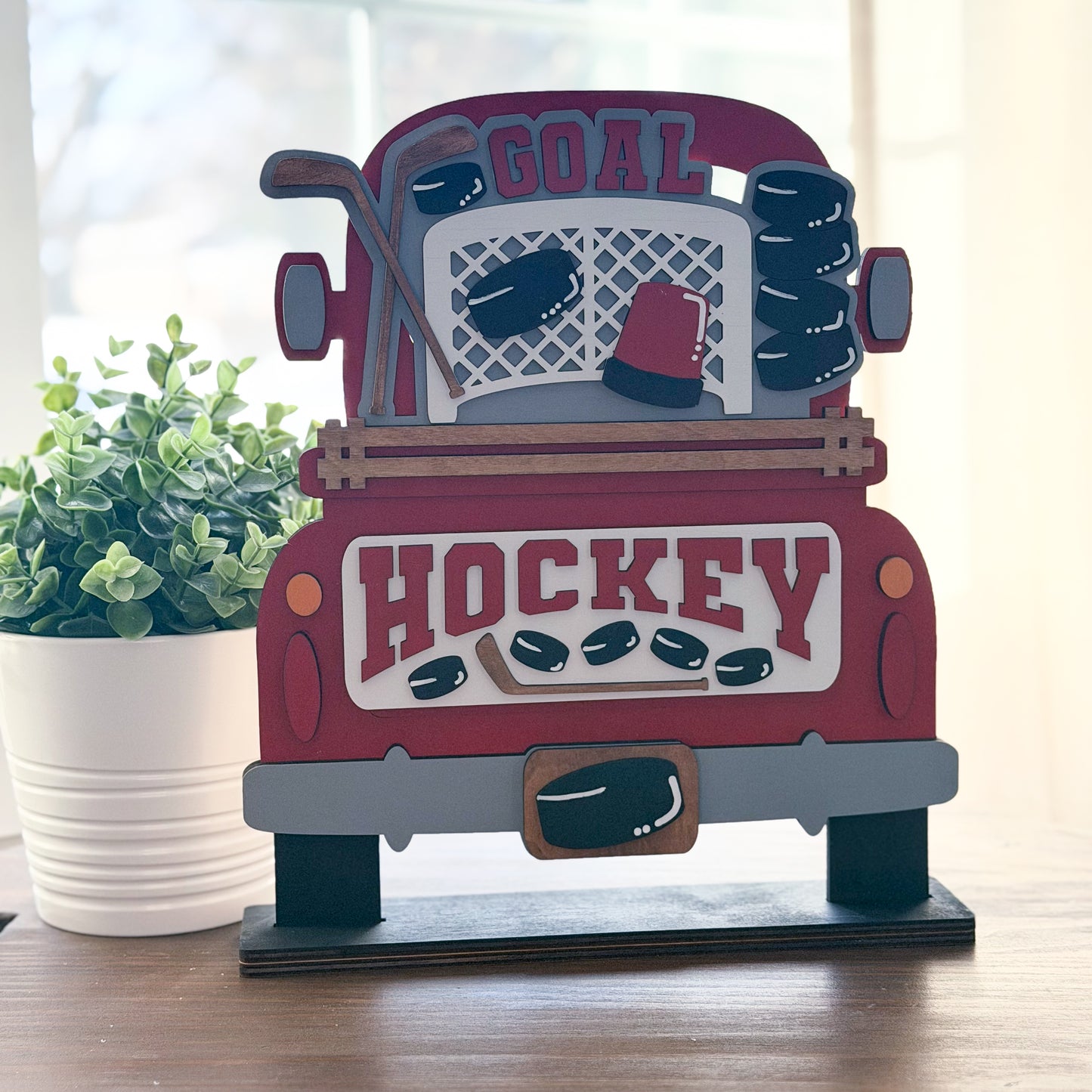Decorative sign shaped like a truck with hockey-themed design on a wooden surface.