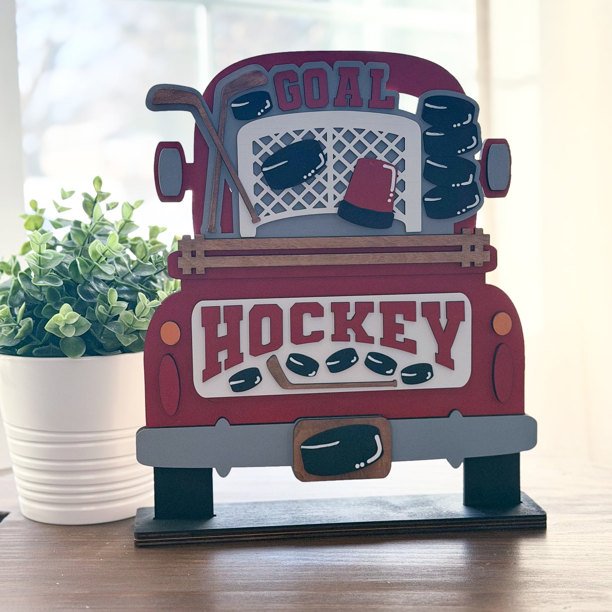 Decorative sign shaped like a truck with hockey-themed design on a wooden surface.