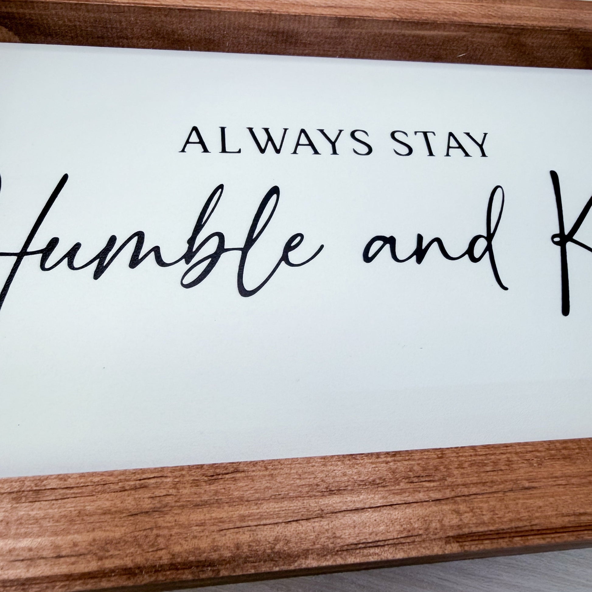 Wooden sign with 'Always stay humble and kind' text on a white background