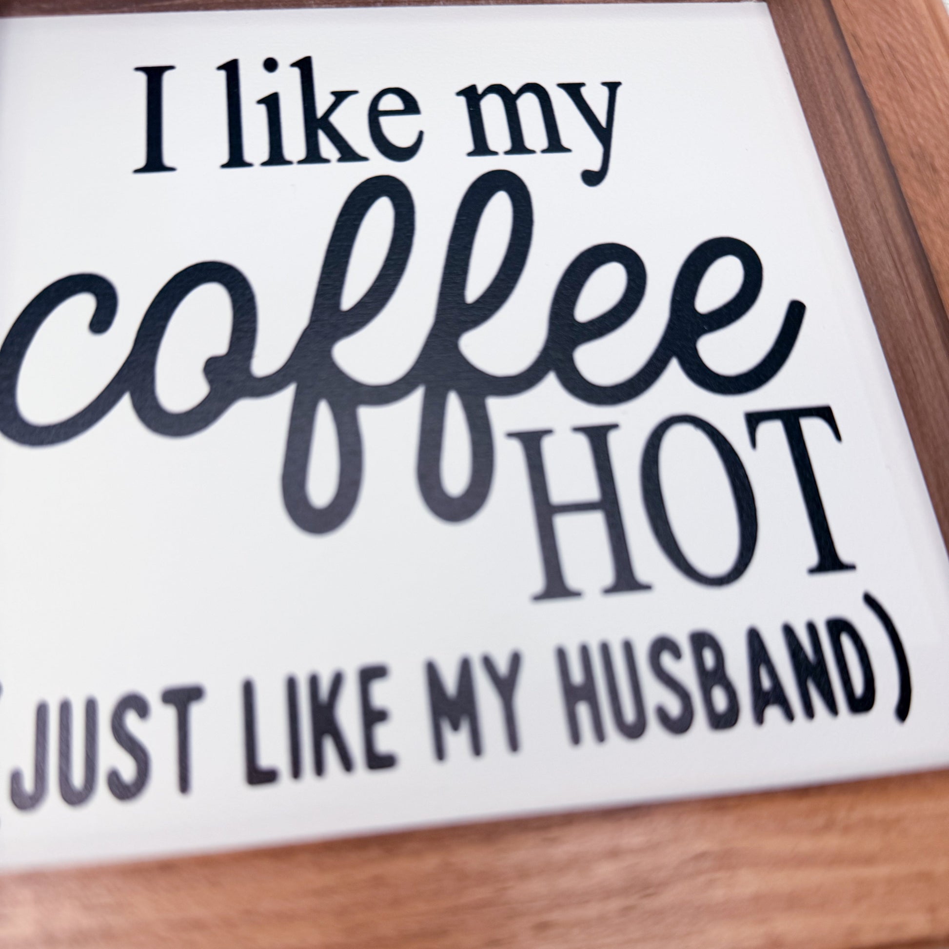 Sign with text 'I like my coffee hot just like my husband' on a wooden surface