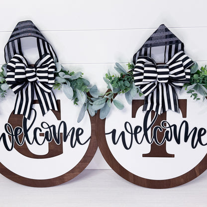 Two wooden signs with 'welcome' text and black and white striped bows on a white background.