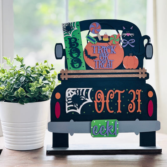 Halloween-themed decorative sign with a truck design on a table.