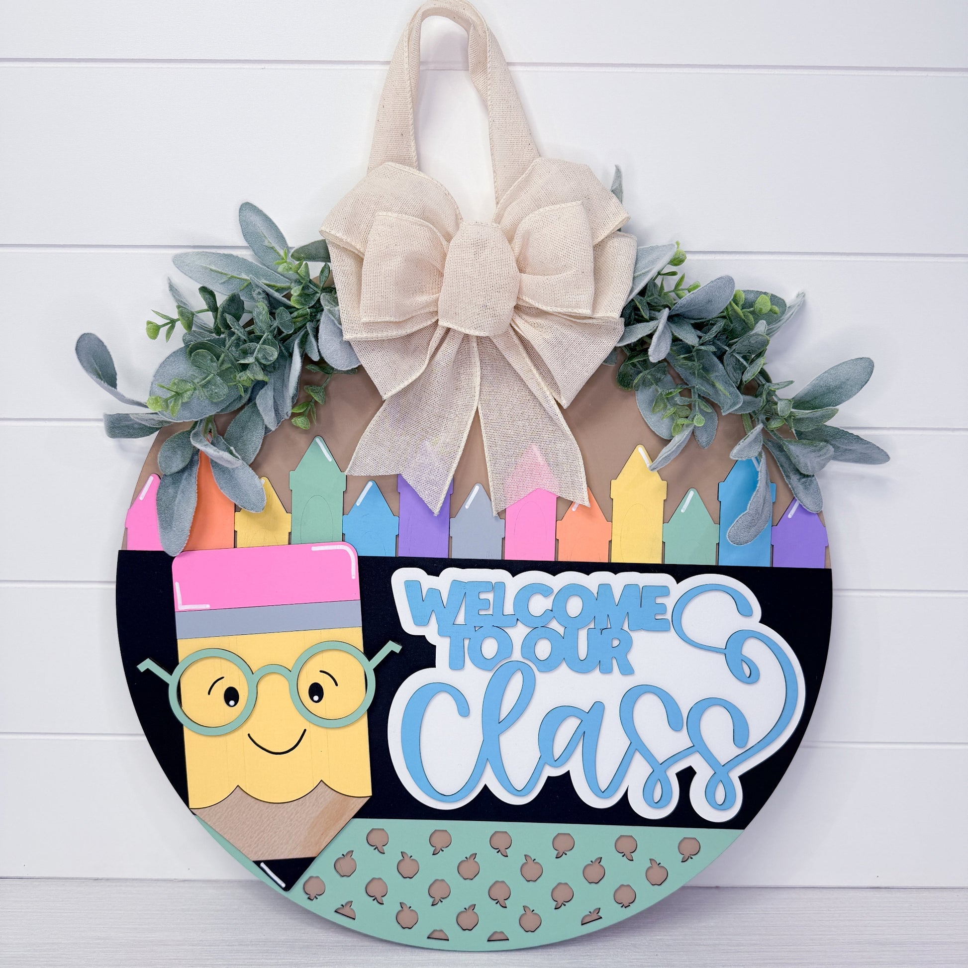 Decorative door hanger with 'Welcome to our Class' text and pencil design on a white wooden background.