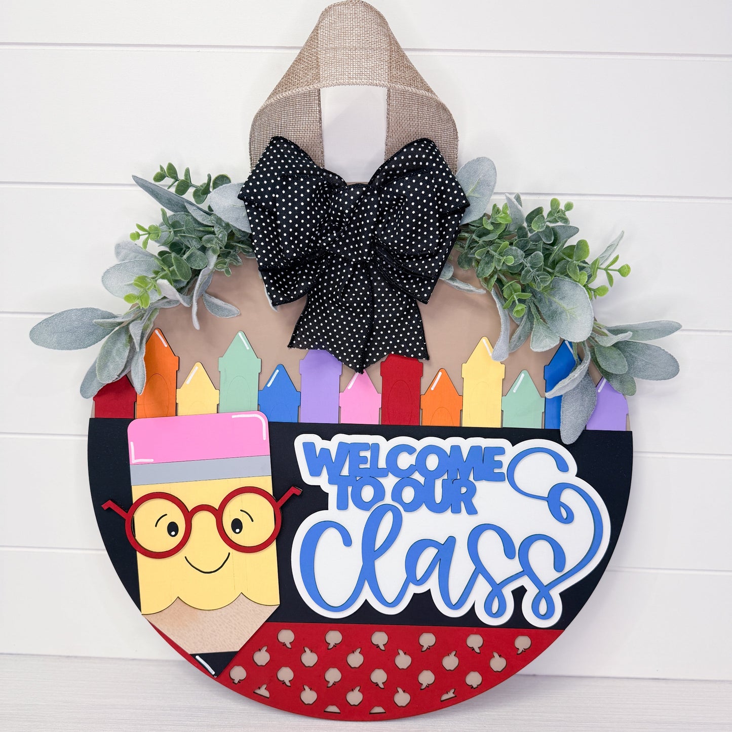 Decorative door hanger with colorful crayons, a pencil, and text 'Welcome to our class' on a white wooden background.