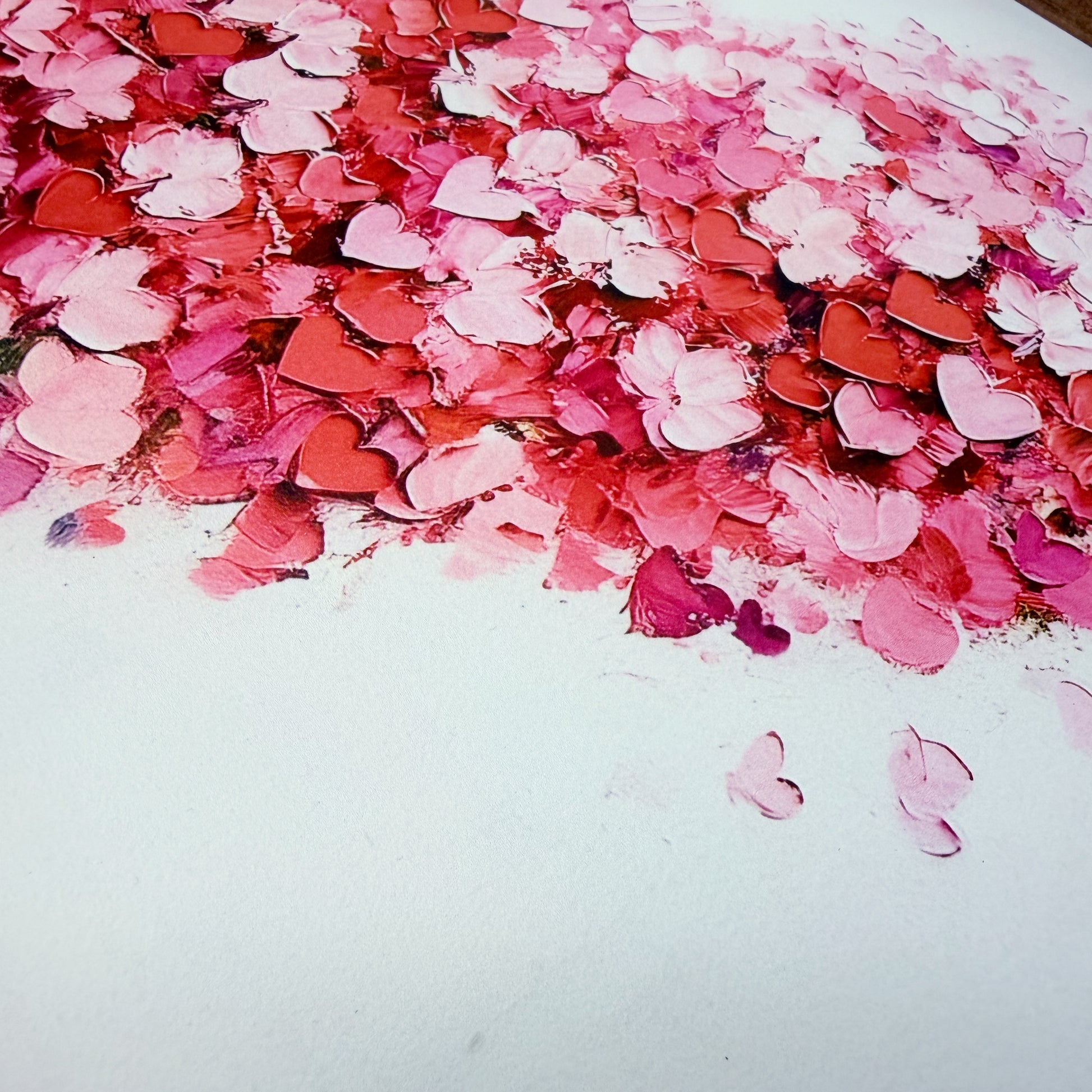 Pink and red heart-shaped confetti on a white surface