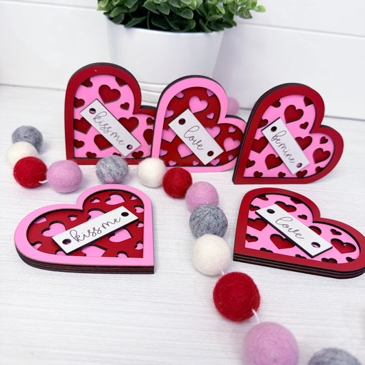 Heart-shaped decorative items with 'love' and 'bless me' text on a white surface
