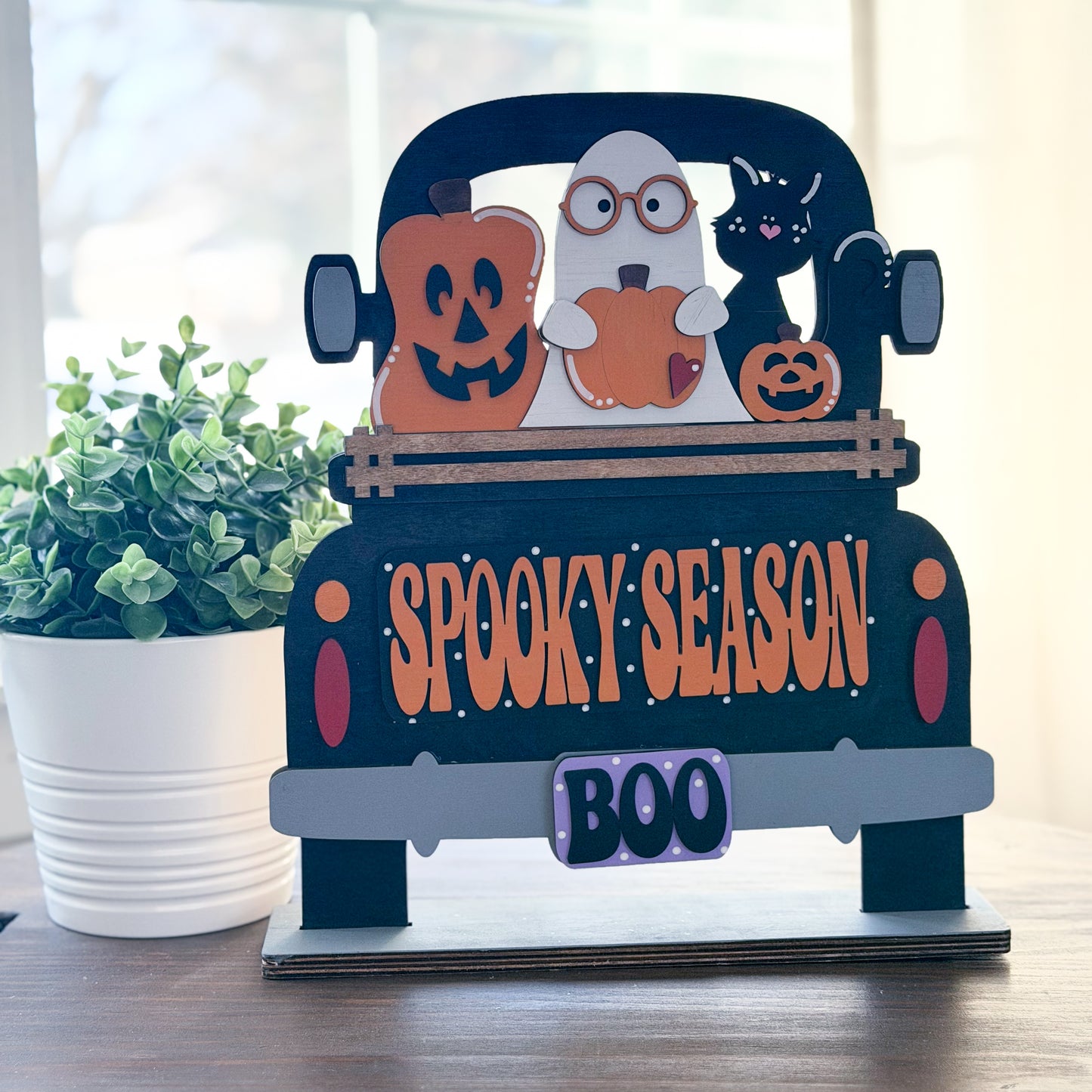 Halloween-themed decorative sign with pumpkins, ghost, and cat on a truck, featuring 'Spooky Season' and 'Boo' text.
