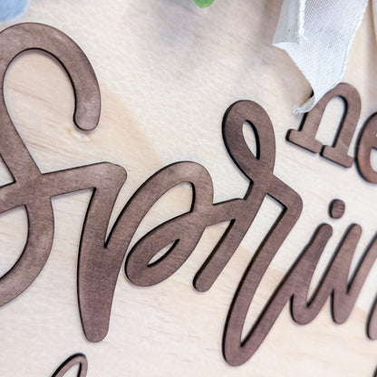 Wooden cutout letters spelling ‘spring' on a light background