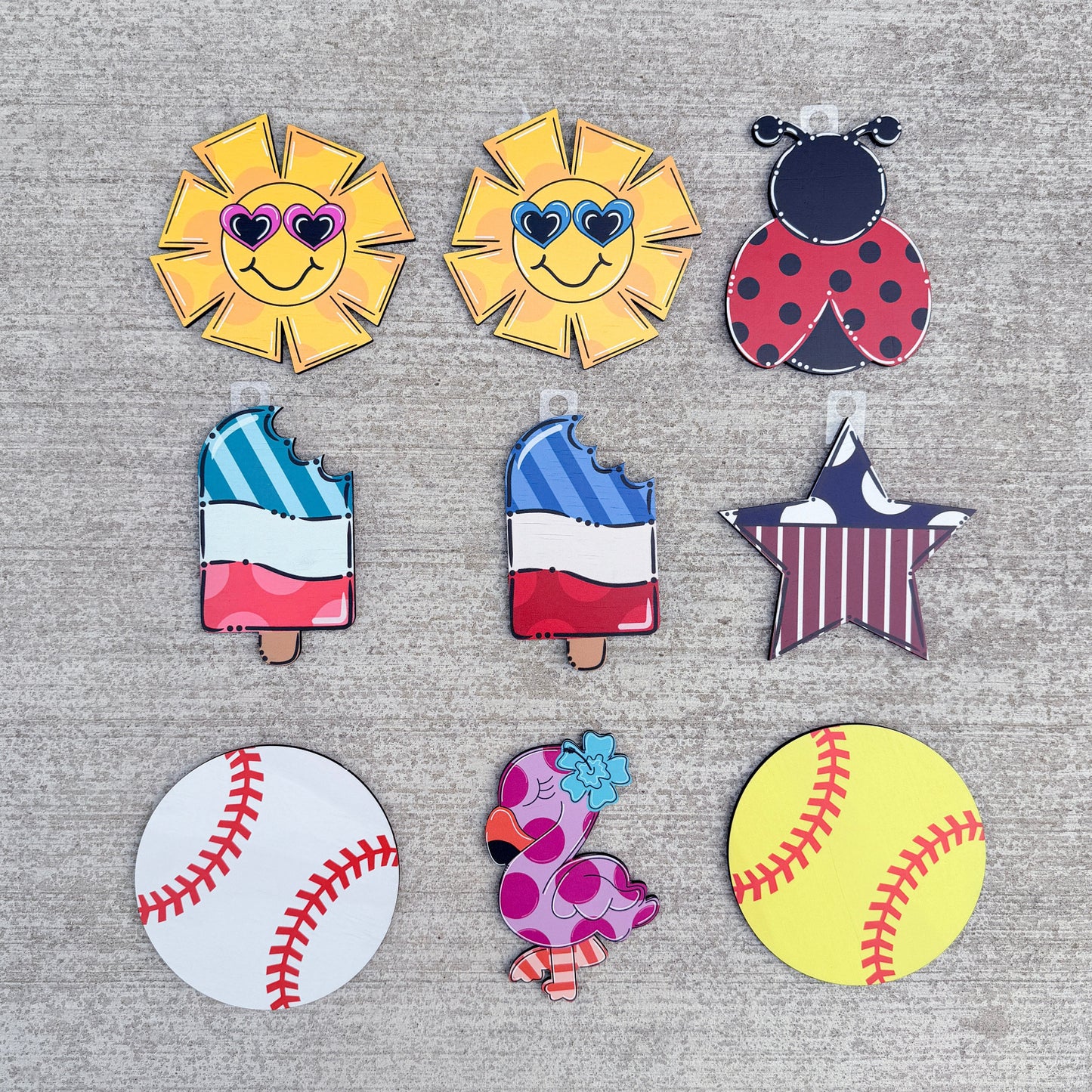  patriotic summer and sports themes, including two smiling yellow suns with sunglasses, a ladybug, two popsicles with a French tricolor design, a star, a baseball, a flamingo, and a yellow softball.
