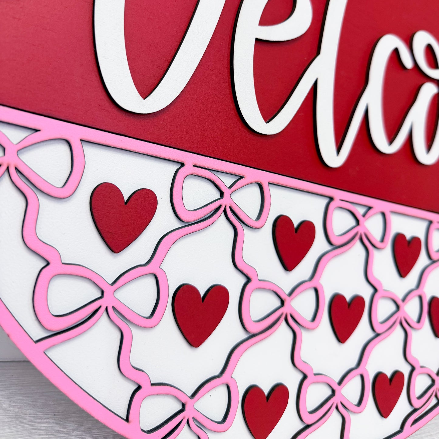 Decorative wood cutout with red hearts and pink bows on a red background