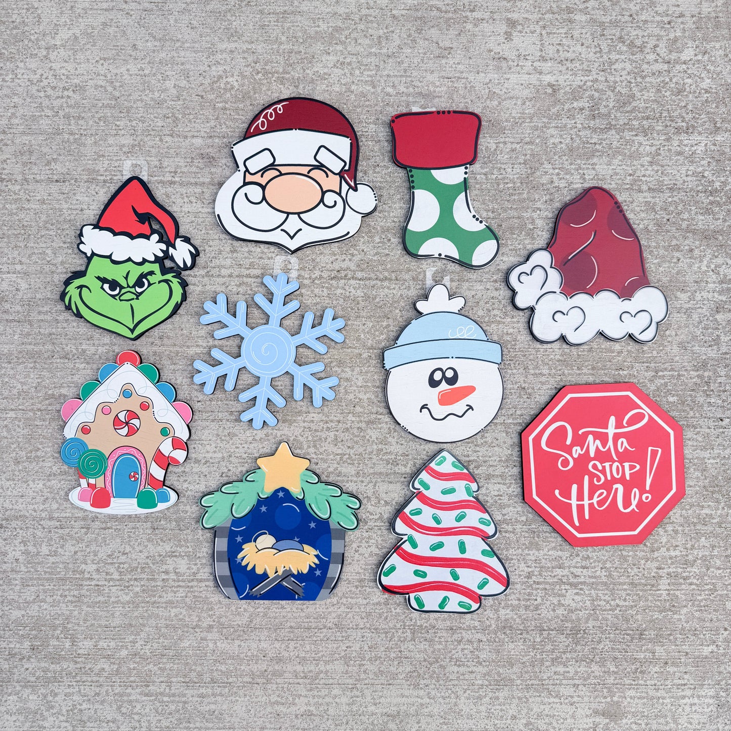 Welcome interchangeable holiday characters and symbols including Grinch, Santa, a stocking, a ham, snowman, gingerbread house, snowflake, nativity scene, Christmas tree, and a red Santa Stop sign.
