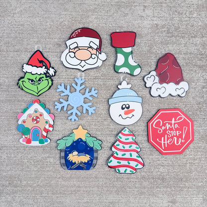 Welcome interchangeable holiday characters and symbols including Grinch, Santa, a stocking, a ham, snowman, gingerbread house, snowflake, nativity scene, Christmas tree, and a red Santa Stop sign.