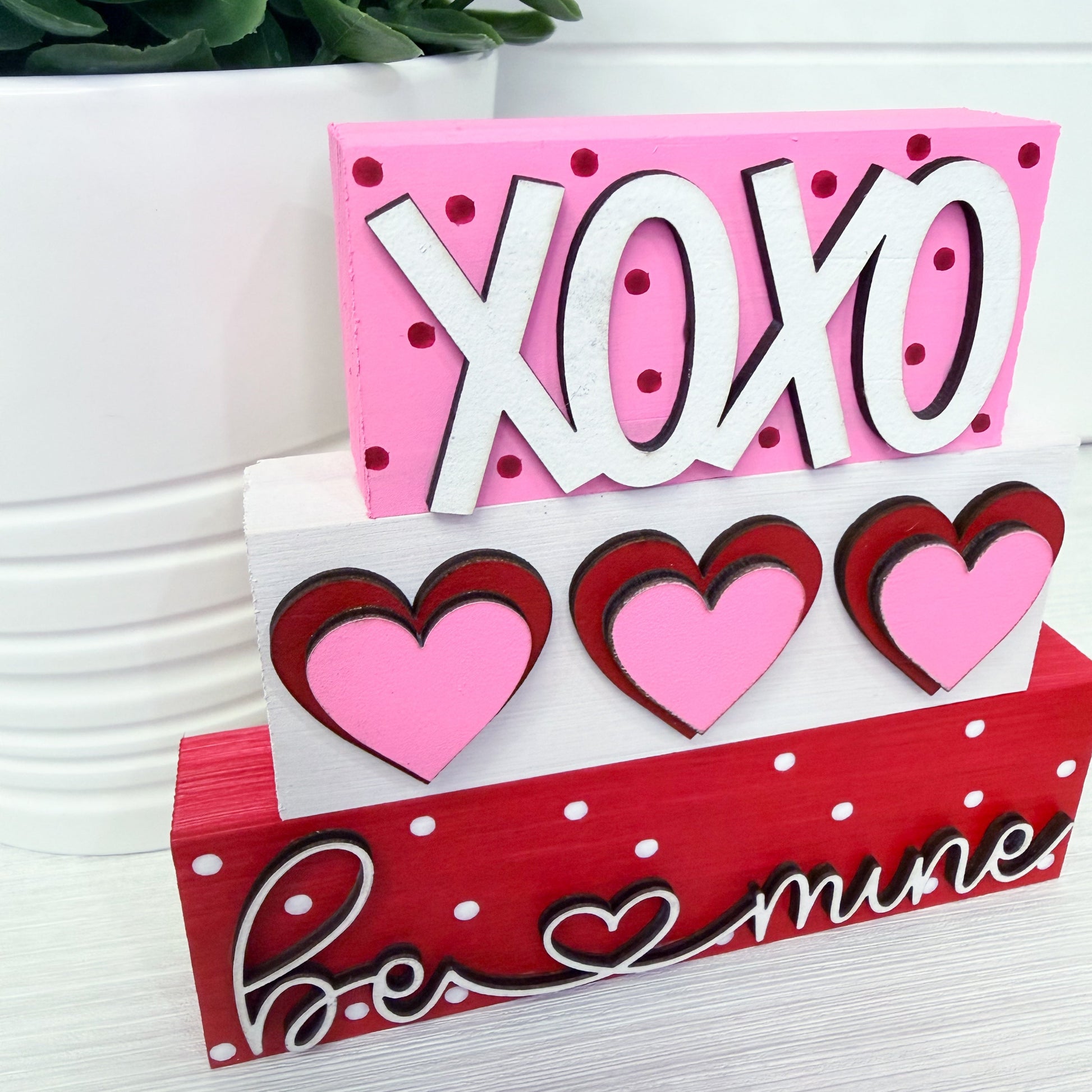 Decorative sign with 'XOXO' and heart designs on a white background