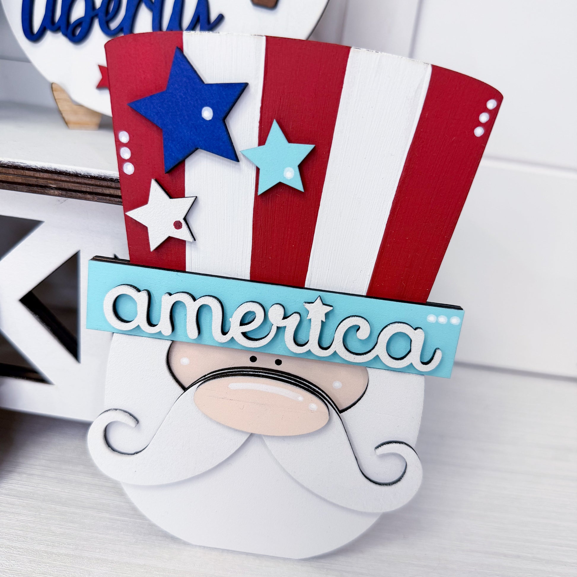 Decorative sign with a gnome face wearing an American flag hat and 'america' text.