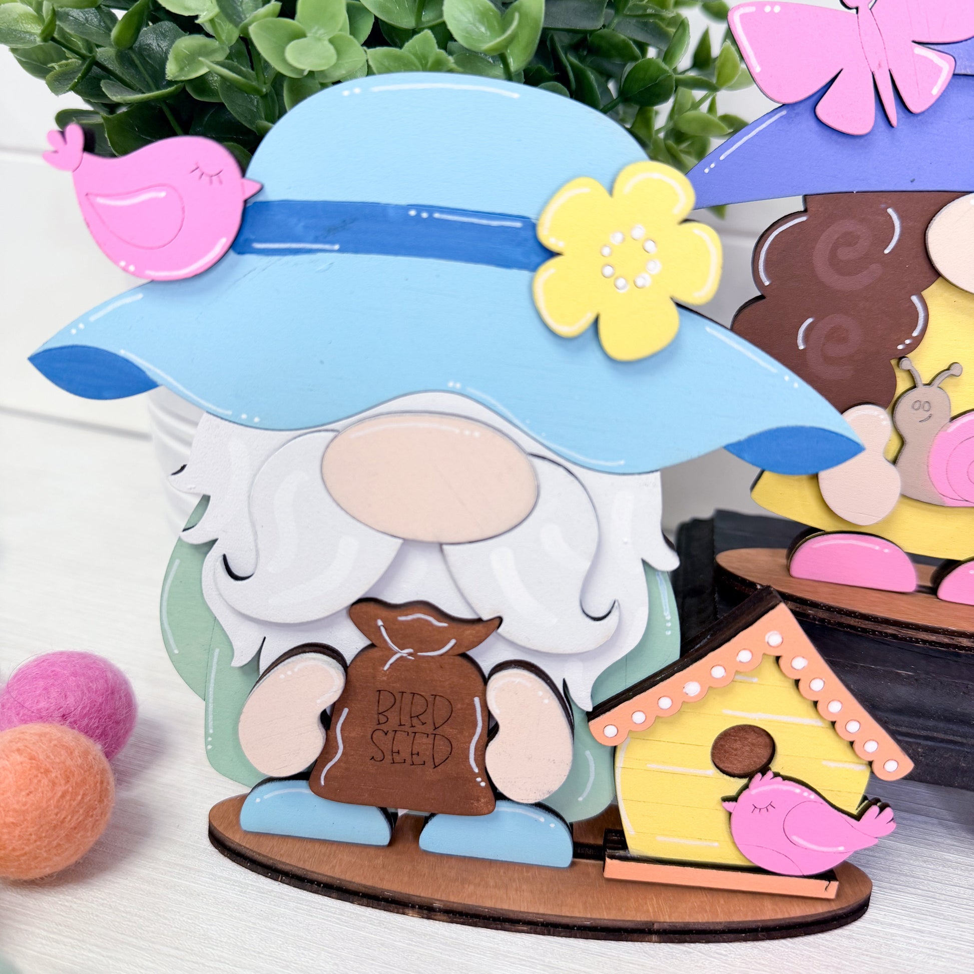 Decorative gnome with a blue hat and bird seed bag, surrounded by small items on a white surface.