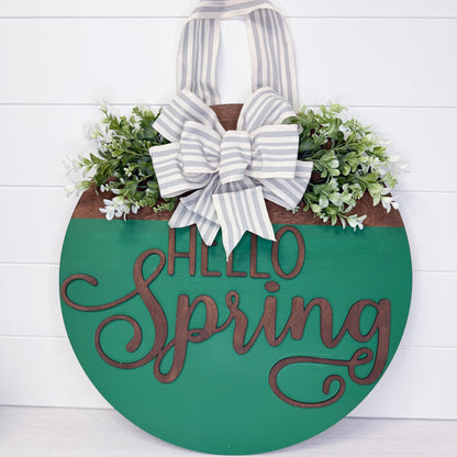 Decorative sign with 'Hello Spring' text and a bow on a white background