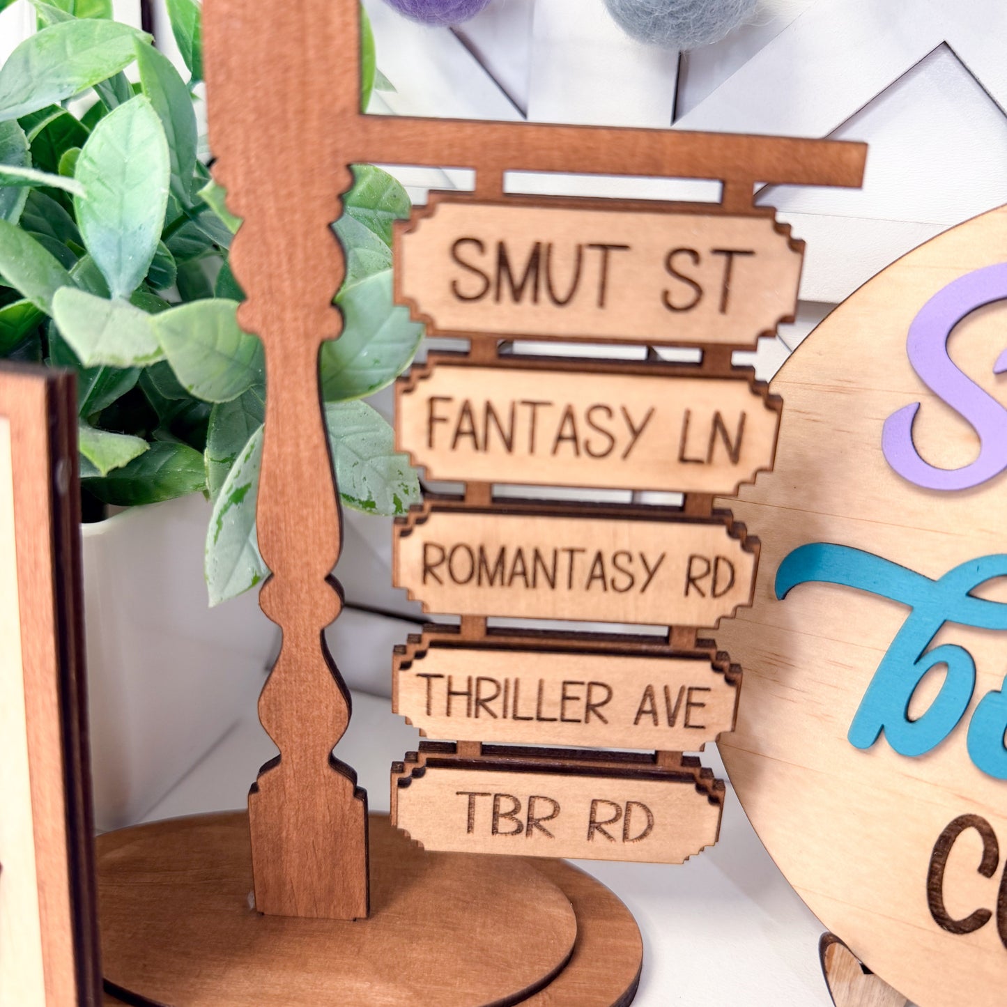Wooden sign with text on a stand with a plant in the background