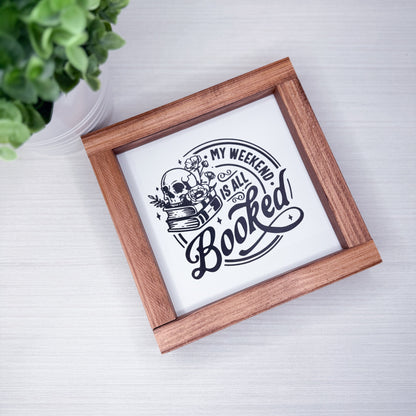 Wooden-framed sign with 'My weekend is all booked' text on a white background