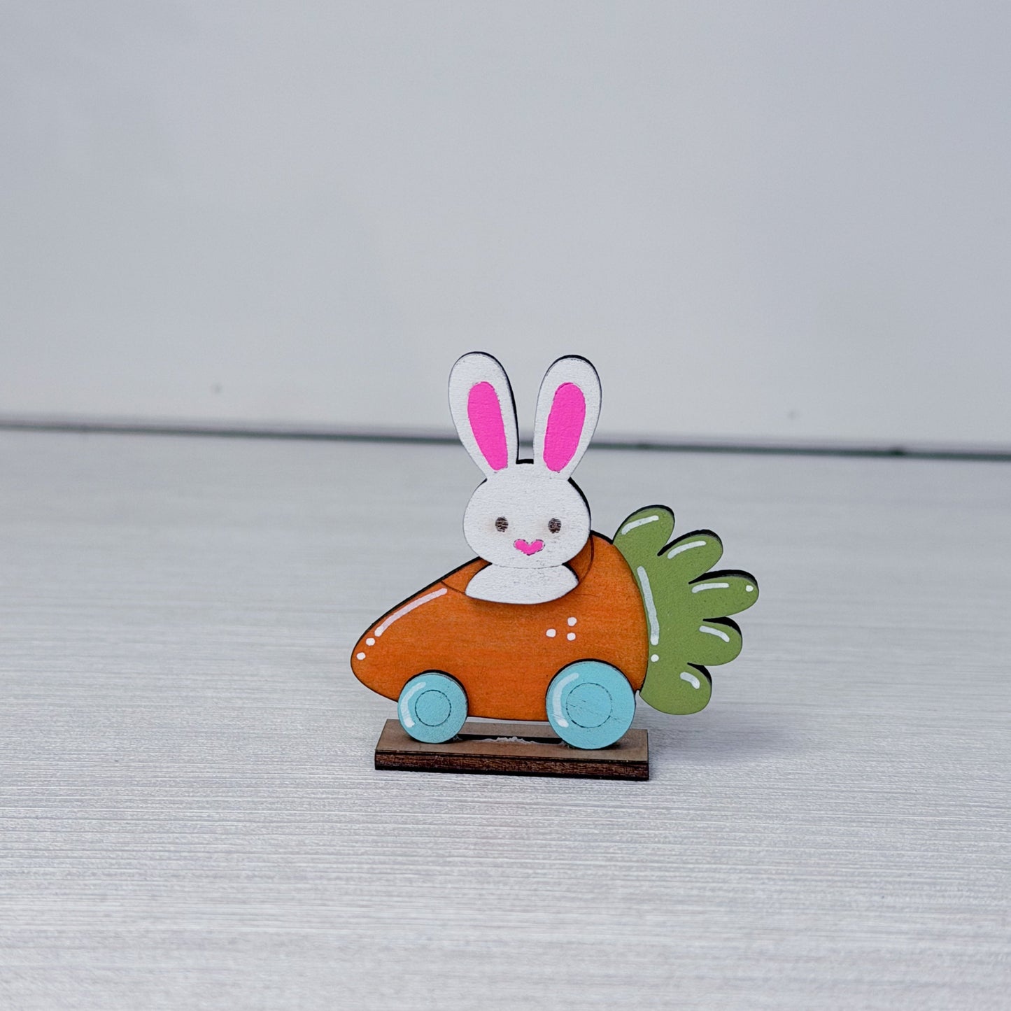 Decorative item with a rabbit in a carrot car on a textured surface