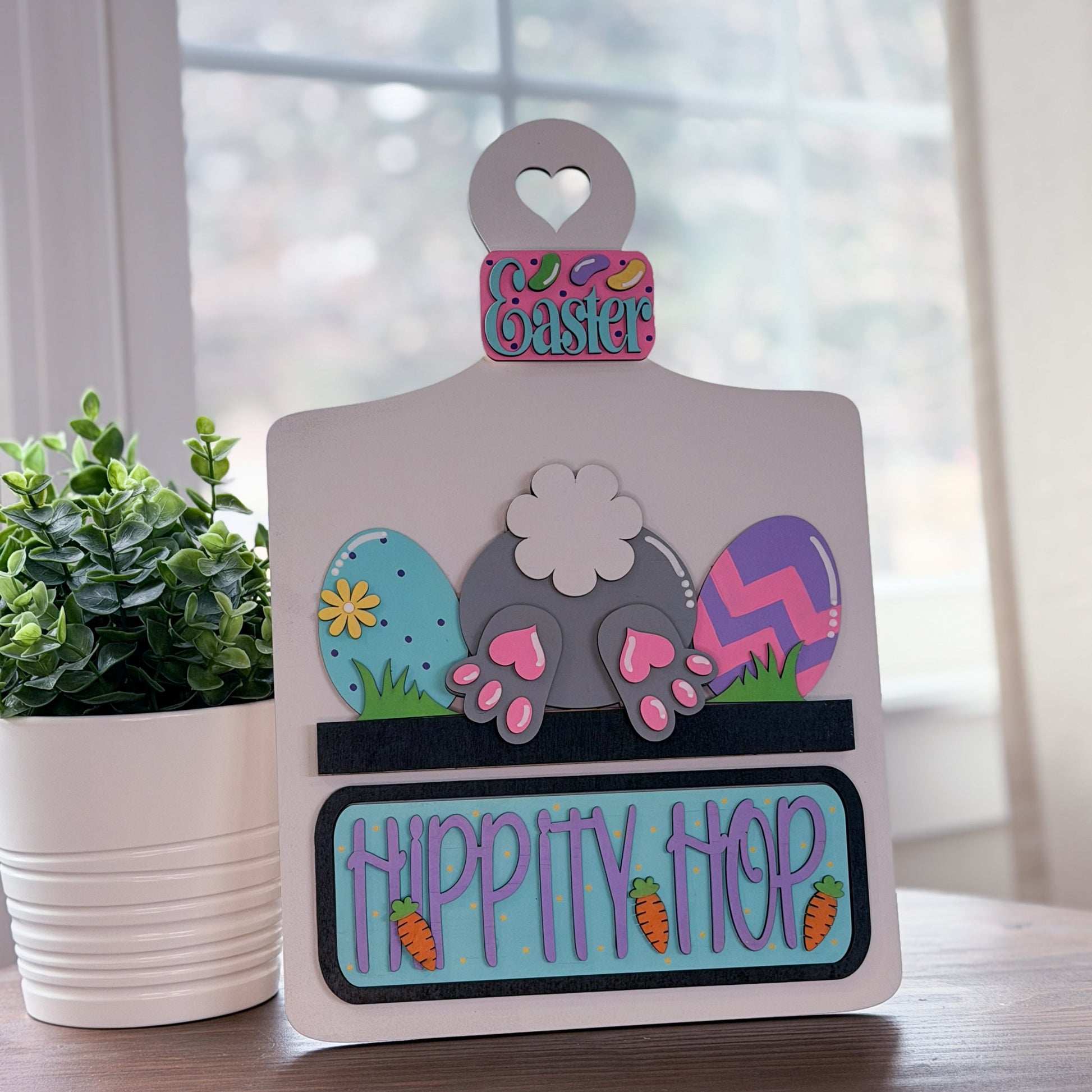 Decorative Easter sign with cartoon mole and colorful text on a wooden surface.