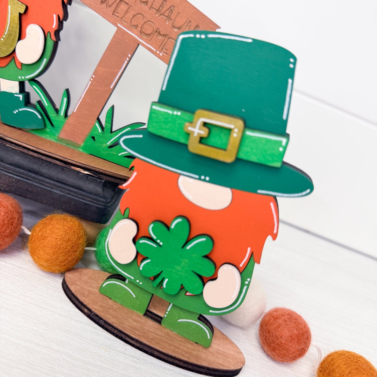 Leprechaun with green hat and orange shirt on a white surface