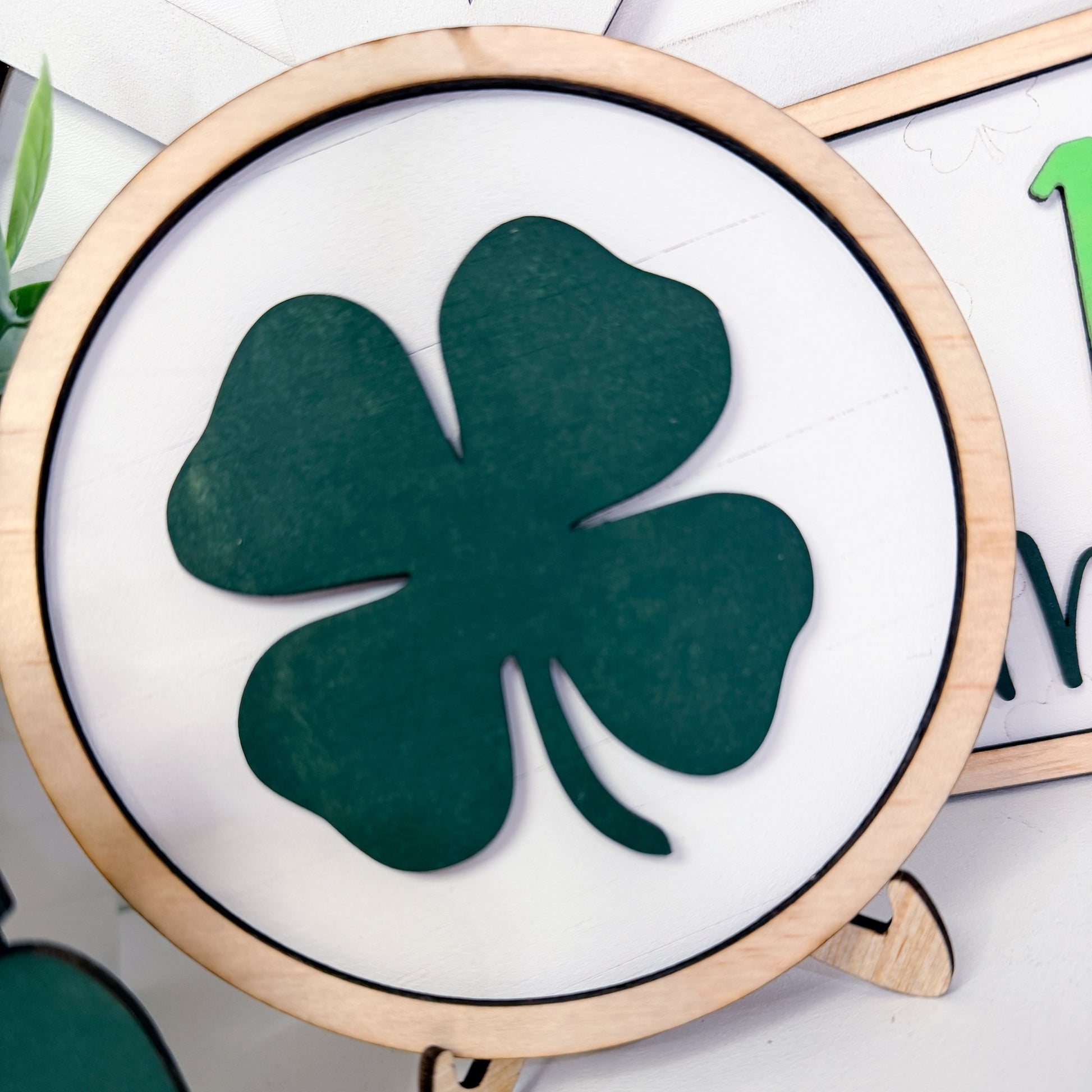 Green four-leaf clover on a white background with a wooden frame.