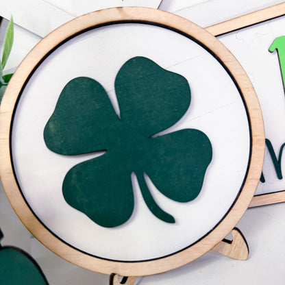 Green four-leaf clover on a white background with a wooden frame.