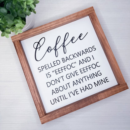 Wooden-framed sign with humorous coffee-themed text on a light background