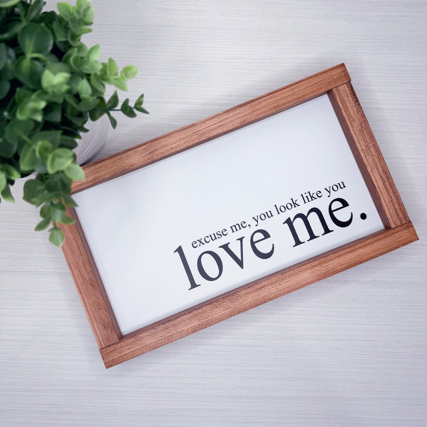 Wooden-framed sign with text 'excuse me, you look like you love me.' on a light background