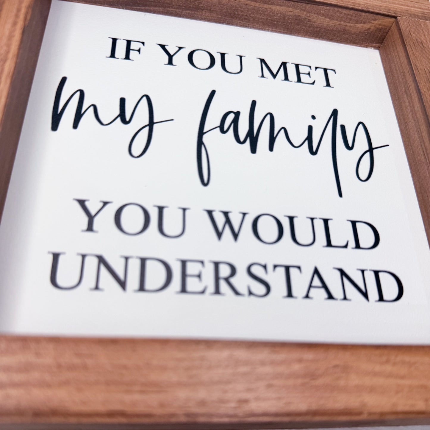 Wooden-framed sign with text 'If you met my family you would understand' on a white background