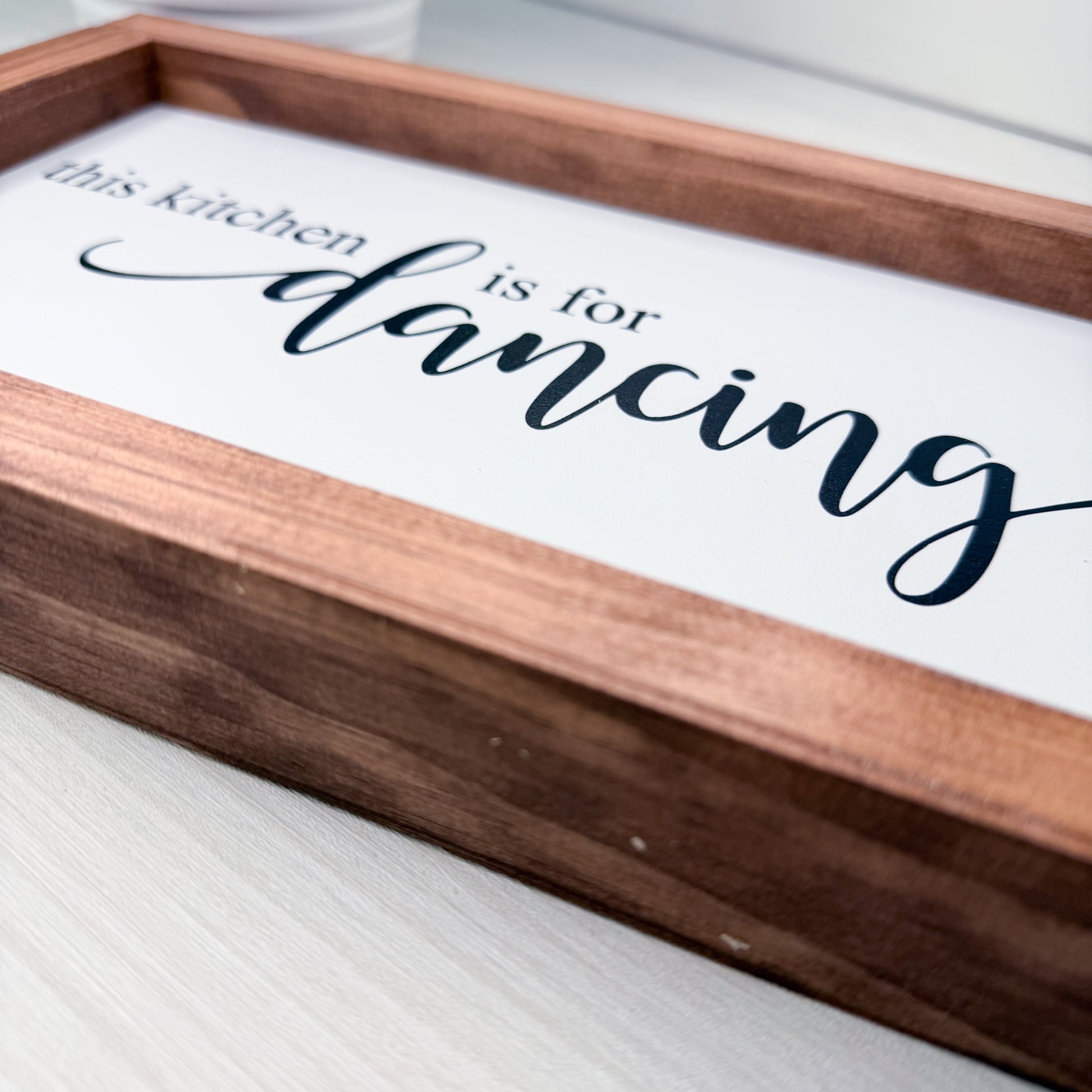 Wooden tray with 'this kitchen is for dancing' text on a white surface