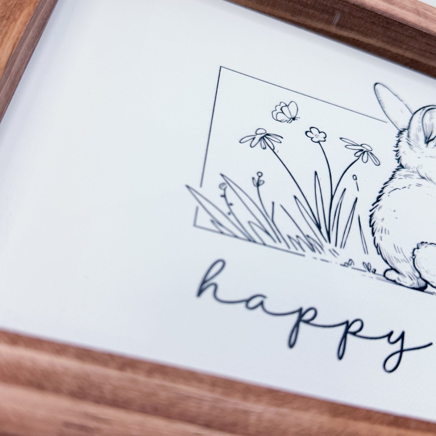 Framed artwork with a rabbit and flowers illustration and the word 'happy'.