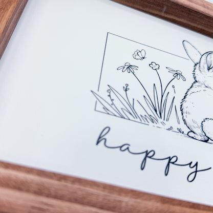 Framed artwork with a rabbit and flowers illustration and the word 'happy'.