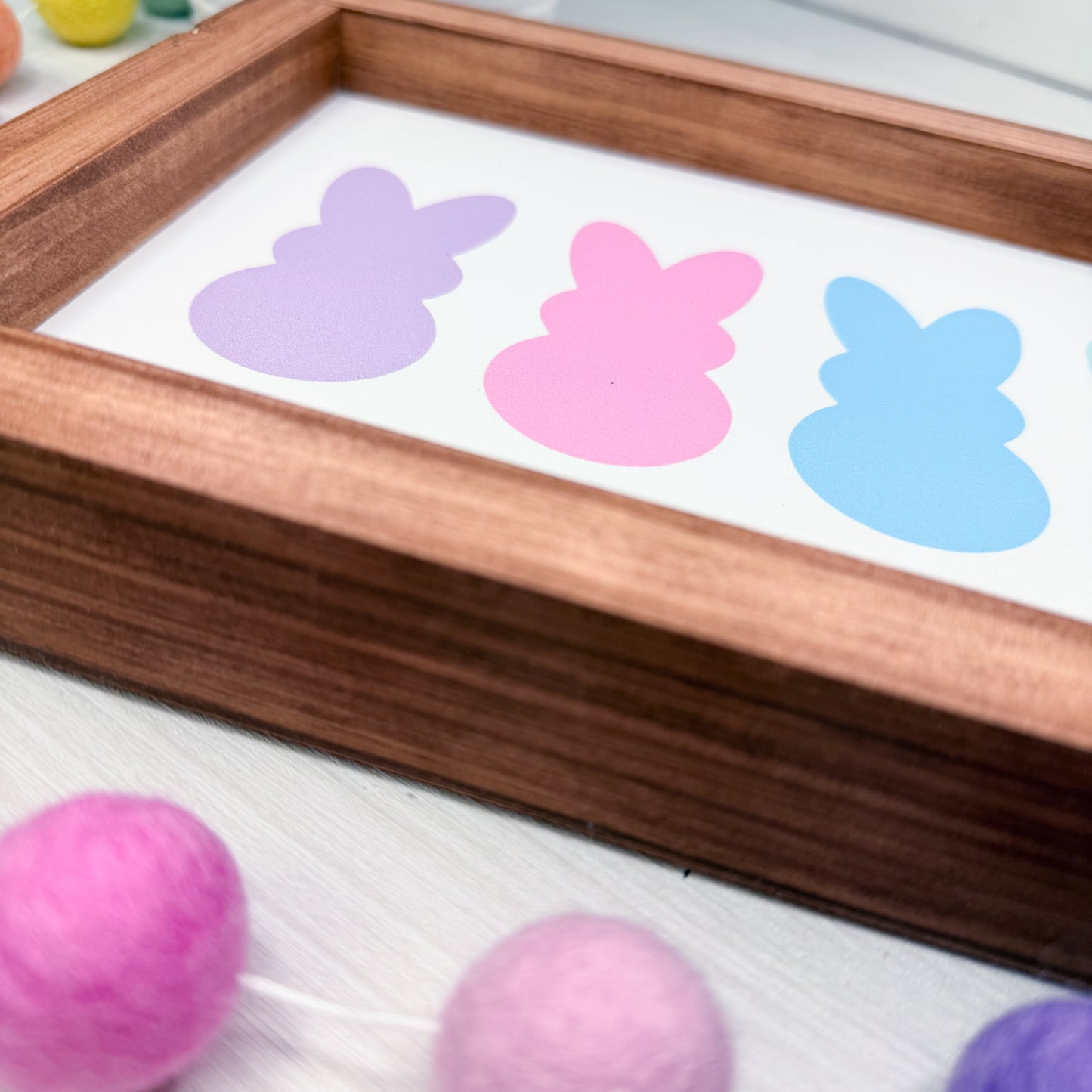 Wooden frame with pastel-colored bunny-shaped stickers on a white background