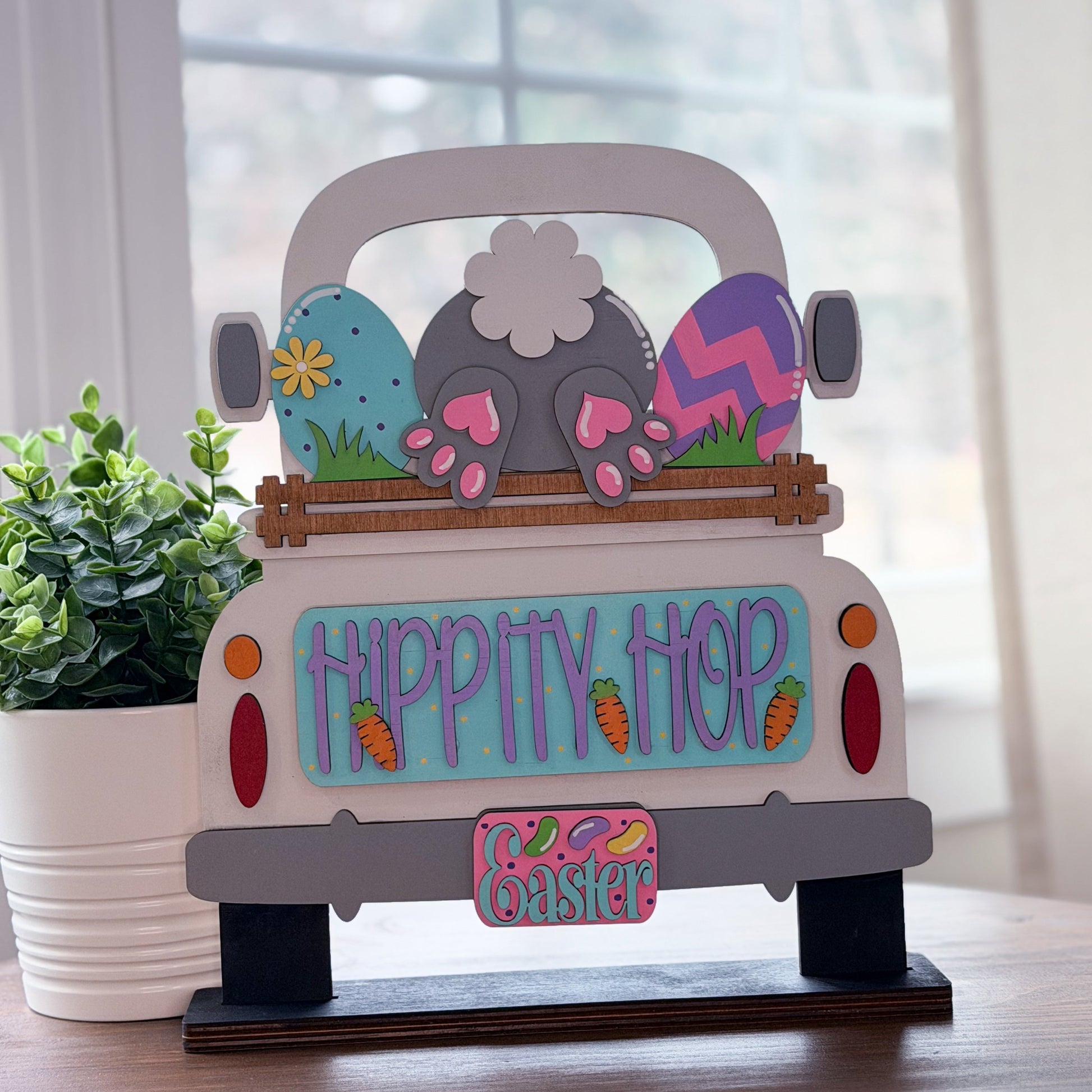 Decorative Easter scene with a truck, eggs, and bunnies on a table.