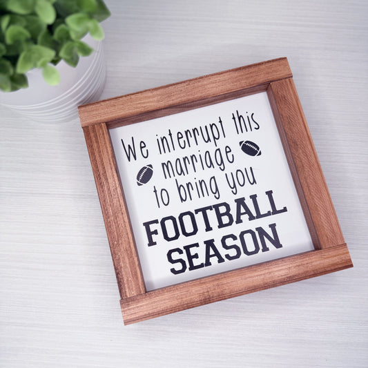 Wooden-framed sign with text about football season on a light background